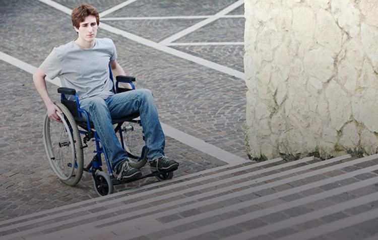 Un joven en una silla de ruedas ante unas escaleras