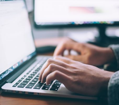 Manos trabajando en el teclado de un ordenador portátil