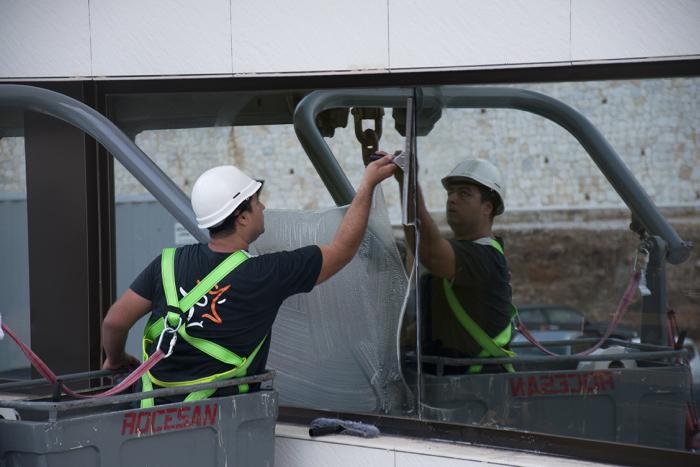 Un operario de Grupo SIFU en una grúa limpiando una ventana de un edificio